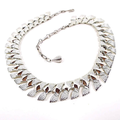Front view of the Modernist style Mid Century vintage Coro choker necklace. The necklace is silver tone in color with angled links that have a diamond pattern on them. There is a hook clasp at the end.