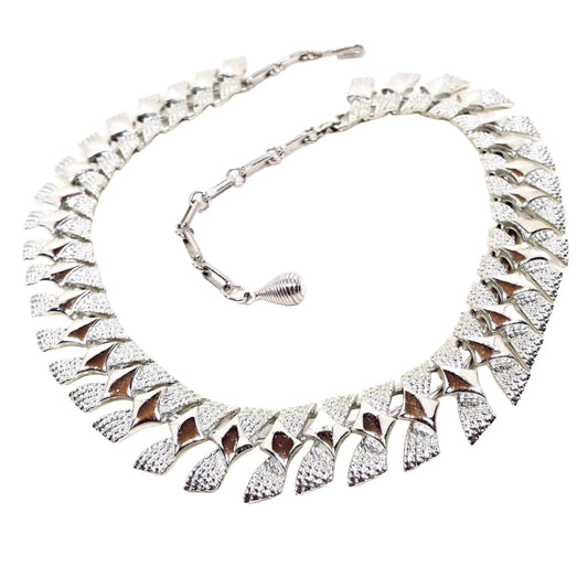 Front view of the Modernist style Mid Century vintage Coro choker necklace. The necklace is silver tone in color with angled links that have a diamond pattern on them. There is a hook clasp at the end.