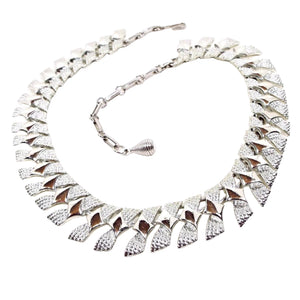Front view of the Modernist style Mid Century vintage Coro choker necklace. The necklace is silver tone in color with angled links that have a diamond pattern on them. There is a hook clasp at the end.