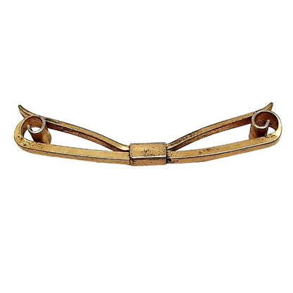 Angled side view of the 1930's curled end collar clip. It is darkened brass in color and has curled in ends and an angled back.