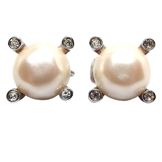 Front view of the retro vintage Avon rhinestone and faux pearl clip on earrings. The imitation pearls are round plastic cabs in an off white color in the middle. There is a round clear rhinestone at each corner of the earrings.