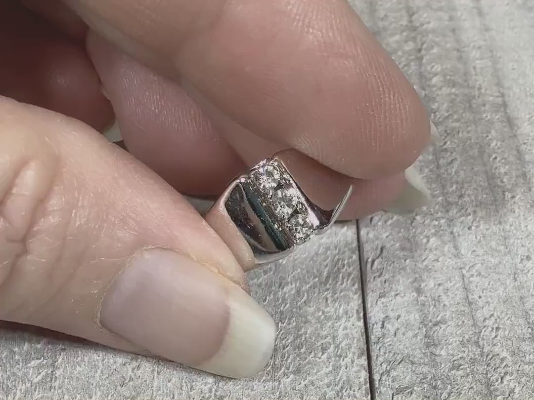 Video showing the sparkle on the rhinestones on this retro vintage ring. The band is angled and flared at the top. There is a line of three small round clear rhinestones.