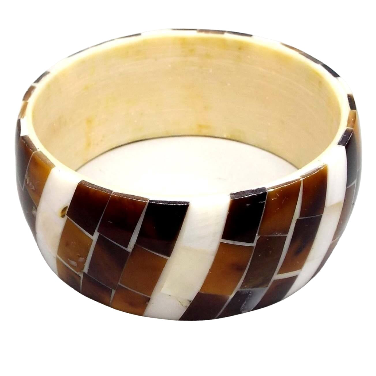 Angled view of the retro vintage wide bone bangle bracelet. The inside layer is bone in an off white yellow color. the outside has inlaid pieces of dyed horn and natural mother of pearl shell.