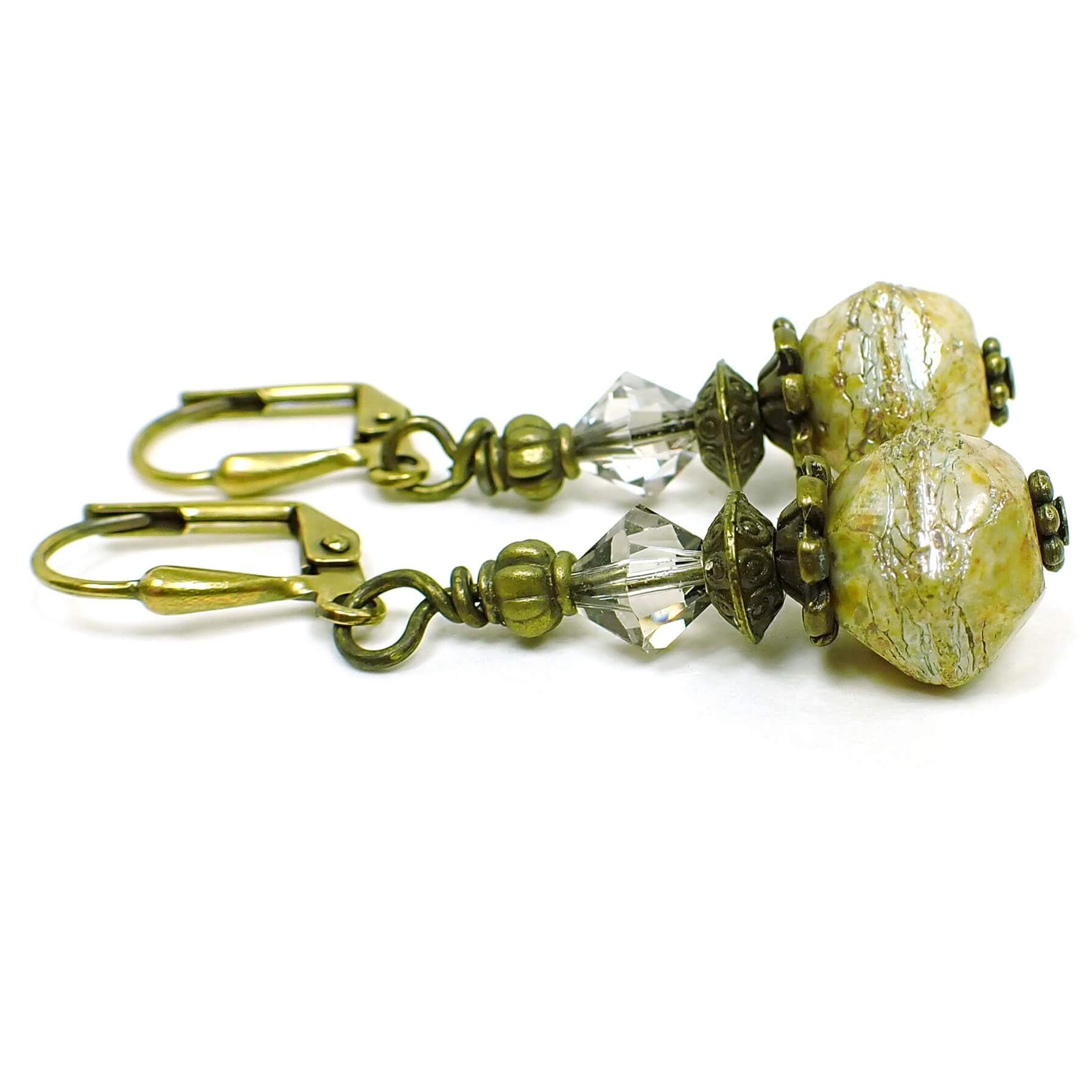 Side view of the multi color Czech glass beaded earrings. The metal is antiqued brass in color. There are very light smoky gray faceted glass crystal beads at the top. The bottom Czech glass beads are a faceted rondelle type shape with shades of yellow, green, and hints of brown in the recesses.