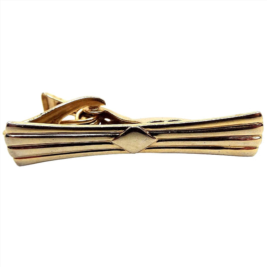 Front view of the Mid Century vintage tie clip with flared ends. The metal is gold tone in color. There is a striped design with ends that flare angled outwards and a diamond shape in the middle. 