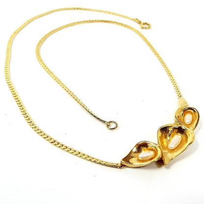 Front view of the retro vintage necklace with floral faux pearl pendant. The metal is gold tone in color. There is a herringbone link chain with a spring ring clasp at the end. At the bottom of the necklace are three flower shaped parts making up the pendant. Each one has a rice shaped imitation pearl in it.