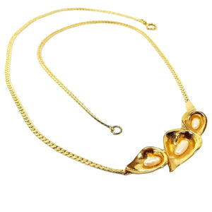Front view of the retro vintage necklace with floral faux pearl pendant. The metal is gold tone in color. There is a herringbone link chain with a spring ring clasp at the end. At the bottom of the necklace are three flower shaped parts making up the pendant. Each one has a rice shaped imitation pearl in it.