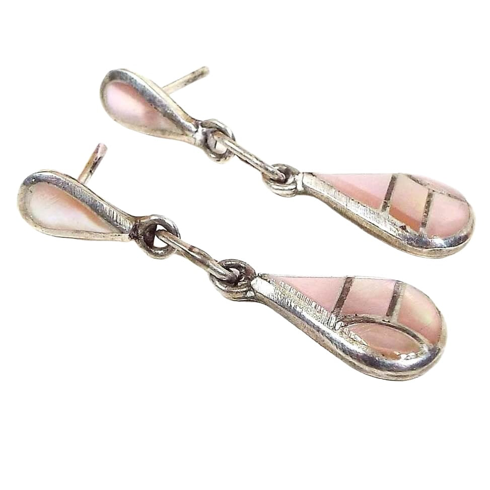 Front view of the retro vintage Southwestern style small teardrop earrings. The metal is silver tone in color. There is a teardrop at the top and another at the bottom pointing different directions. Each has inlaid mother of pearl shell that is dyed a light pink in color.