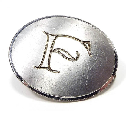 Front view of the smaller length retro vintage Swank initial tie clip. It is silver tone in color with a matte front and oval in shape. The letter F is engraved on the front.