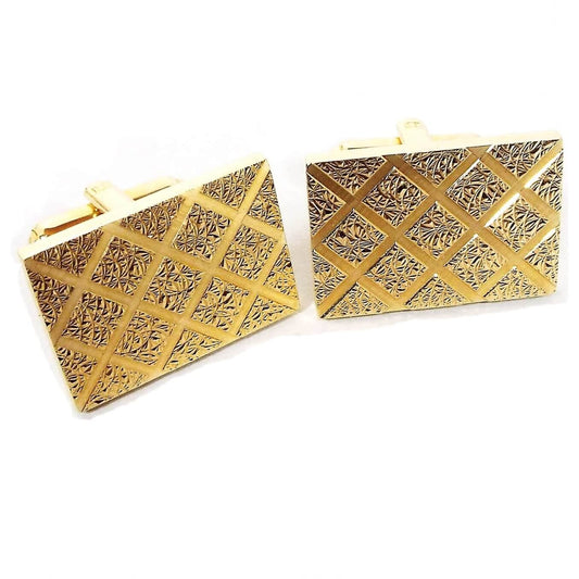 Front view of the Mid Century vintage Simmons Karatclad cufflinks. They are gold tone in color and rectangle in shape. The front has a raised textured design with a cut diamond shaped pattern throughout the front.