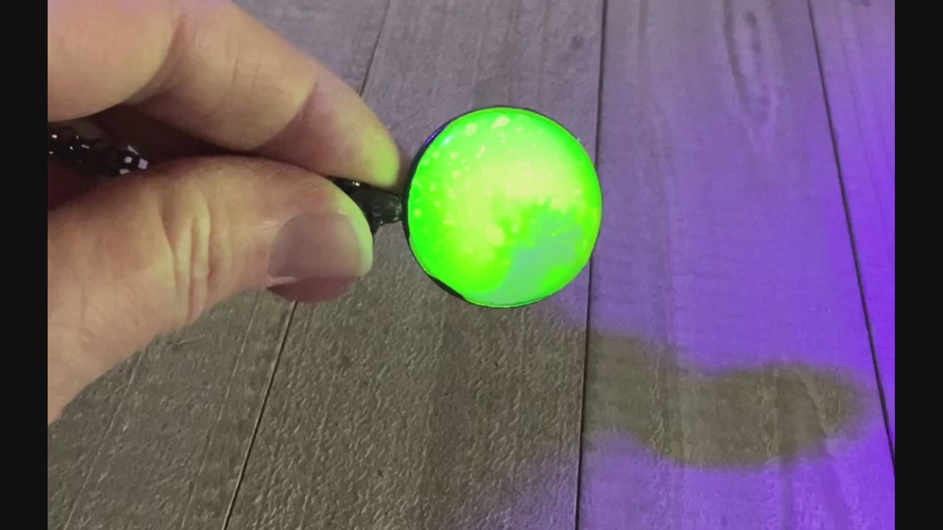 Video showing the neon yellow in the handmade resin pendant fluorescing bright green under a UV black light.