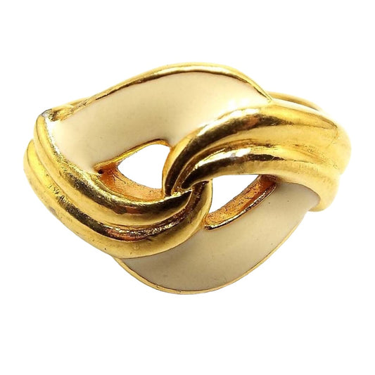 Front view of the retro vintage enameled ring. The metal is gold tone in color. The top has a twist design with curves of cream color enameled metal in the back with curves of gold tone metal over the front.