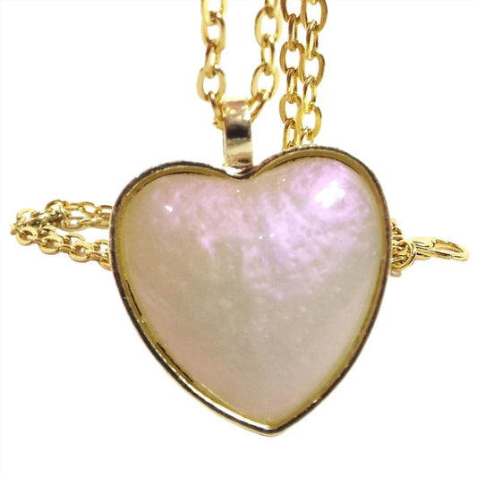 Front view of the handmade pendant with pink color shift resin. The metal is gold tone plated in color. The pendant is heart shaped and has pearly resin with hues of off white yellow and flashes of pink.