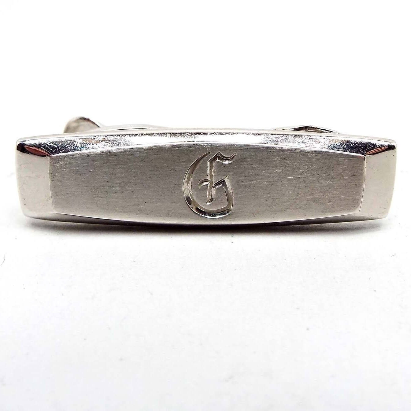 Front view of the Mid Century vintage Hickok initial tie clip. It is silver tone in color with the letter G engraved on the front.