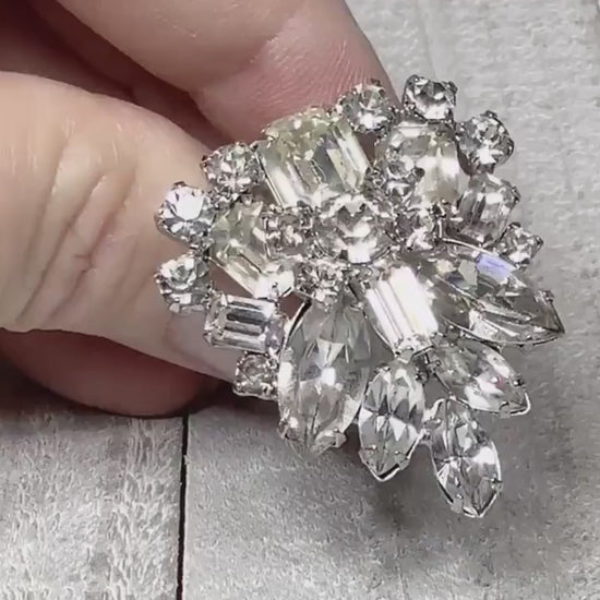 Video of the Mid Century vintage rhinestone fur clip. It has an upside down triangle like design with round, marquis, and rectangle clear rhinestones. The video is showing how they sparkle.