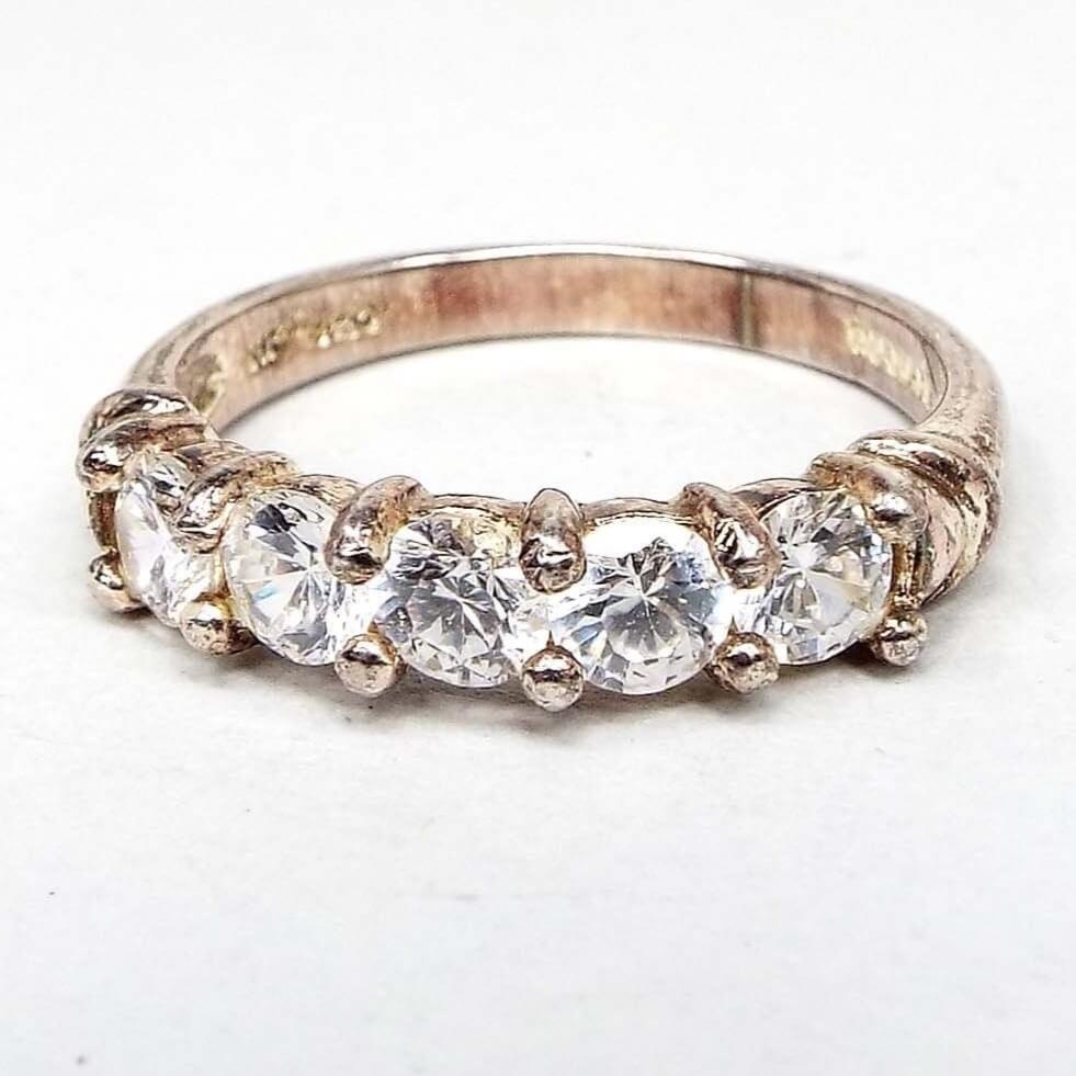 Front view of the retro vintage sterling silver cubic zirconia band ring. The sterling has a slightly darkened patina from age. There are five round prong set CZ stones at the top in a line around the top of the ring. 