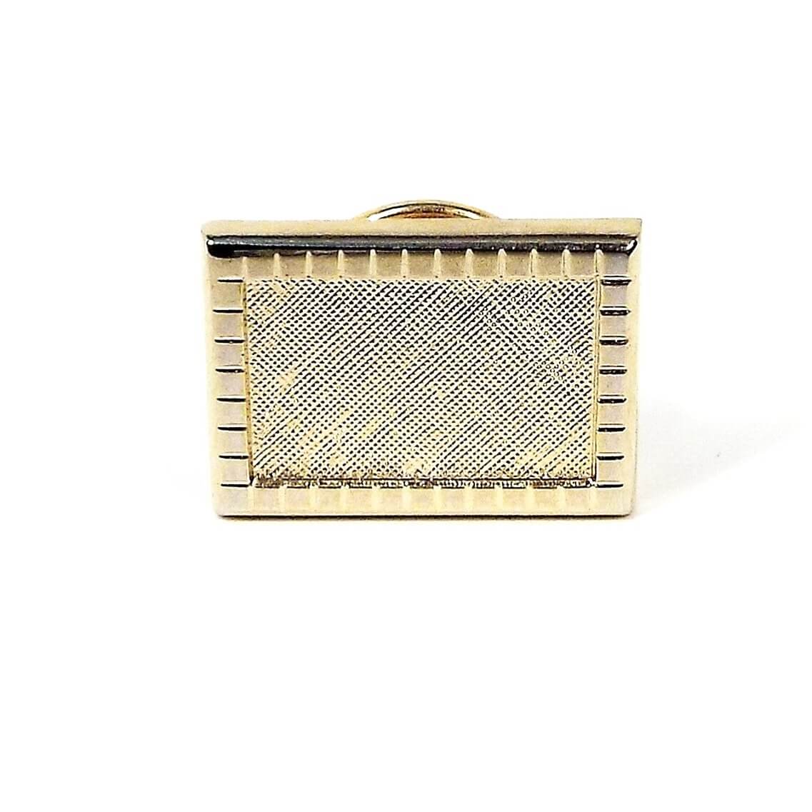 Front view of the retro vintage tie tack. The metal is gold tone plated in color. It is rectangle shaped with a square pattern around the outer edge. The inside front has a matte textured design.