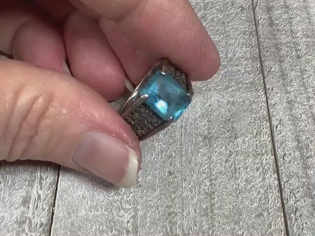 Video showing the sparkle on the sterling silver retro vintage rhinestone and marcasite ring. The sterling has a darkened patina. There is a large rectangle blue rhinestone on top with rows of small round marcasite stones on either side.