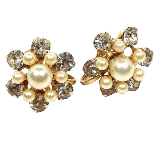 Front view of the Mid Century vintage faux pearl and rhinestone screw back earrings. They have a flower like design with round off white imitation pearls in the middle and clear round rhinestones around the edge.