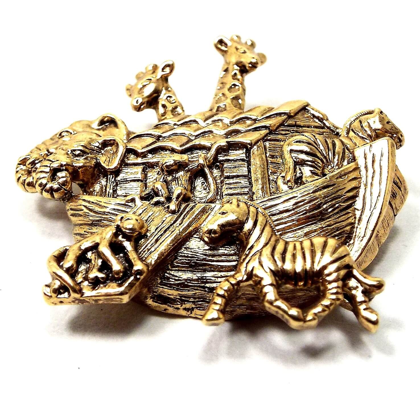 Front view of the retro vintage 1990's Avon Noah's Ark brooch pin. It is antiqued gold tone in color and has a depiction of Noah's Ark with animals on it. 
