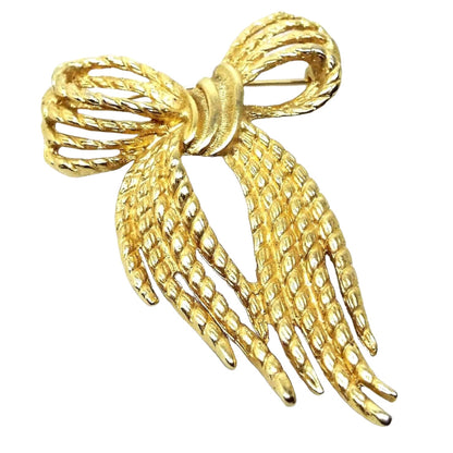 Front view of the retro vintage bow brooch. The metal is gold tone in color and has a textured appearance. It is shaped like a tied Holiday bow.