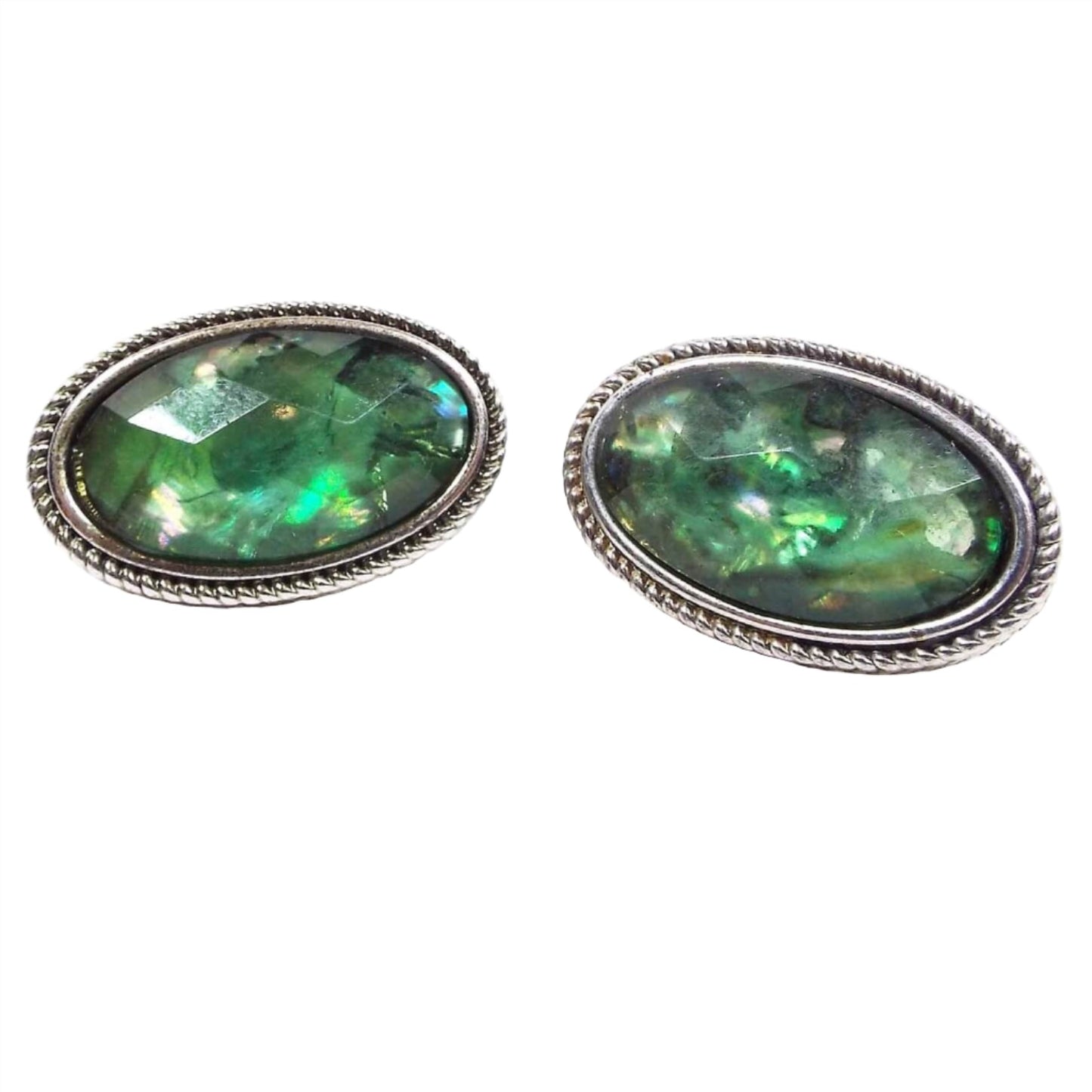 Front view of the retro vintage JJG Napier clip on earrings. The metal is silver tone in color. They are oval shaped and have faceted plastic cabs that have an imitation opal like appearance.