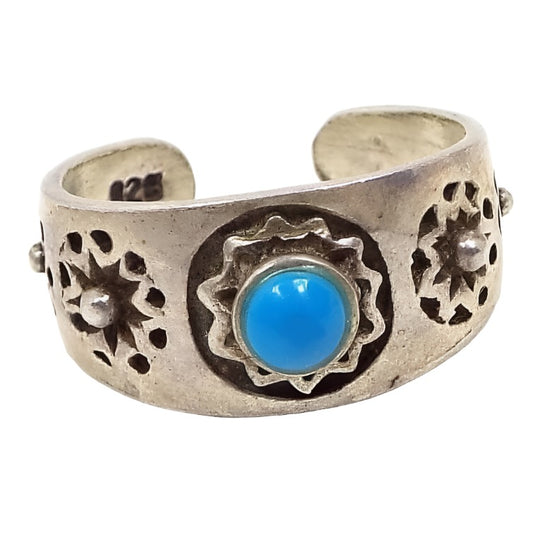 Front view of the retro vintage Southwestern style Boho sterling silver toe ring with faux turquoise. The sterling band has rounded open back to adjust the size and is marked 925 on the inside end of the band. There is a sun design on the front with a blue glass imitation turquoise cab. There is a starburst style design on each side of that.