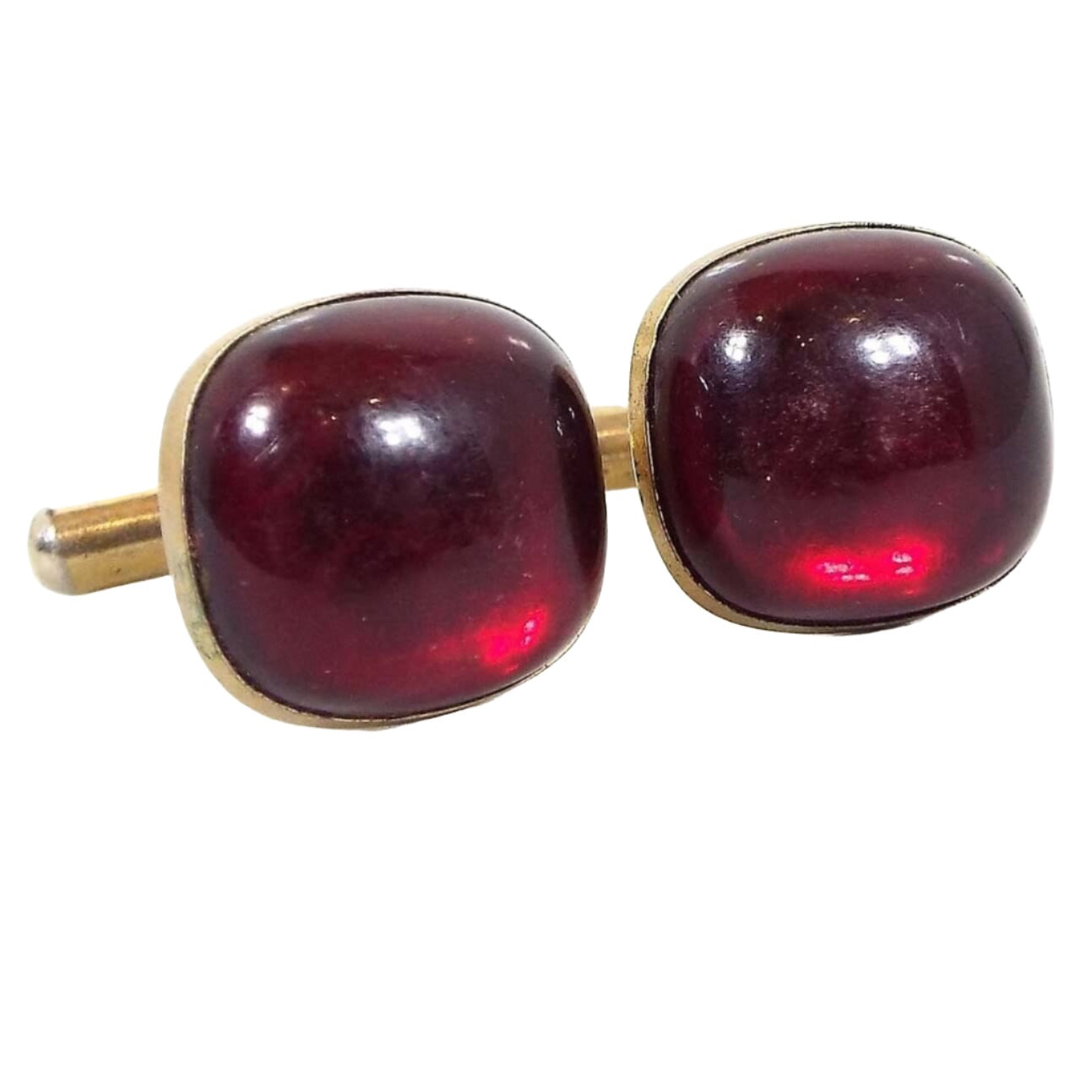 Front view of the Mid Century vintage lucite cufflinks. The metal is gold tone in color and they have a rounded square shape. The fronts have domed red lucite cabs that are semi translucent.