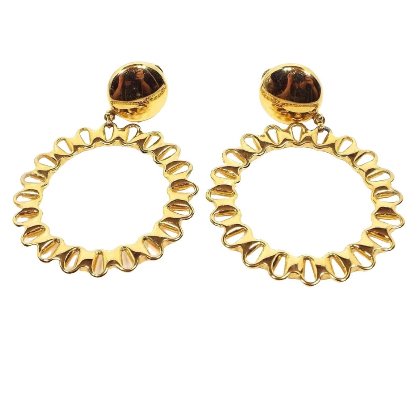 Front view of the retro vintage Monet clip on hoop earrings. The metal is gold tone in color. There is a round shiny area at the top where the clips are and large hoops dangling at the bottoms with a cut out teardrop shape design all the way around the hoops.