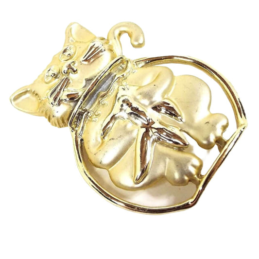Front view of the AJC retro vintage cat in fish bowl brooch pin. The metal is matte gold tone in color except for the fish bowl which is shiny. The cat is sitting in the fish bowl with his head and tail out and he's holding the goldfish in the bowl.