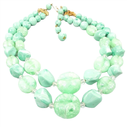 Front view of the 1960's. Coro multi strand necklace. It has two strands beaded with chunky style plastic beads in mint green. Some of the beads are opaque and some have semi translucent swirls. There is a gold tone hook clasp at the end.
