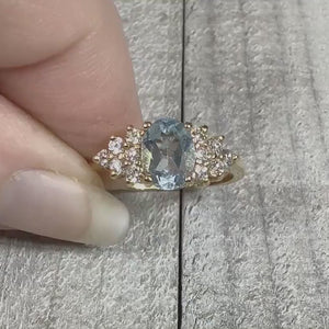 Video of the retro vintage cocktail ring and how the stones sparkle. The metal is light gold tone in color. There is an oval light blue topaz stone at the top with small round clear cubic zirconia stones on the sides.