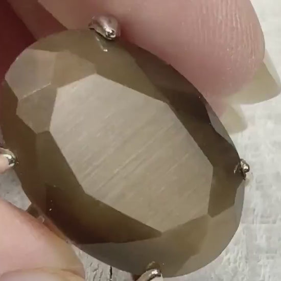 Video showing the flash on the imitation cats eye retro vintage ring. The faux cat's eye stone is a large oval faceted and brown.
