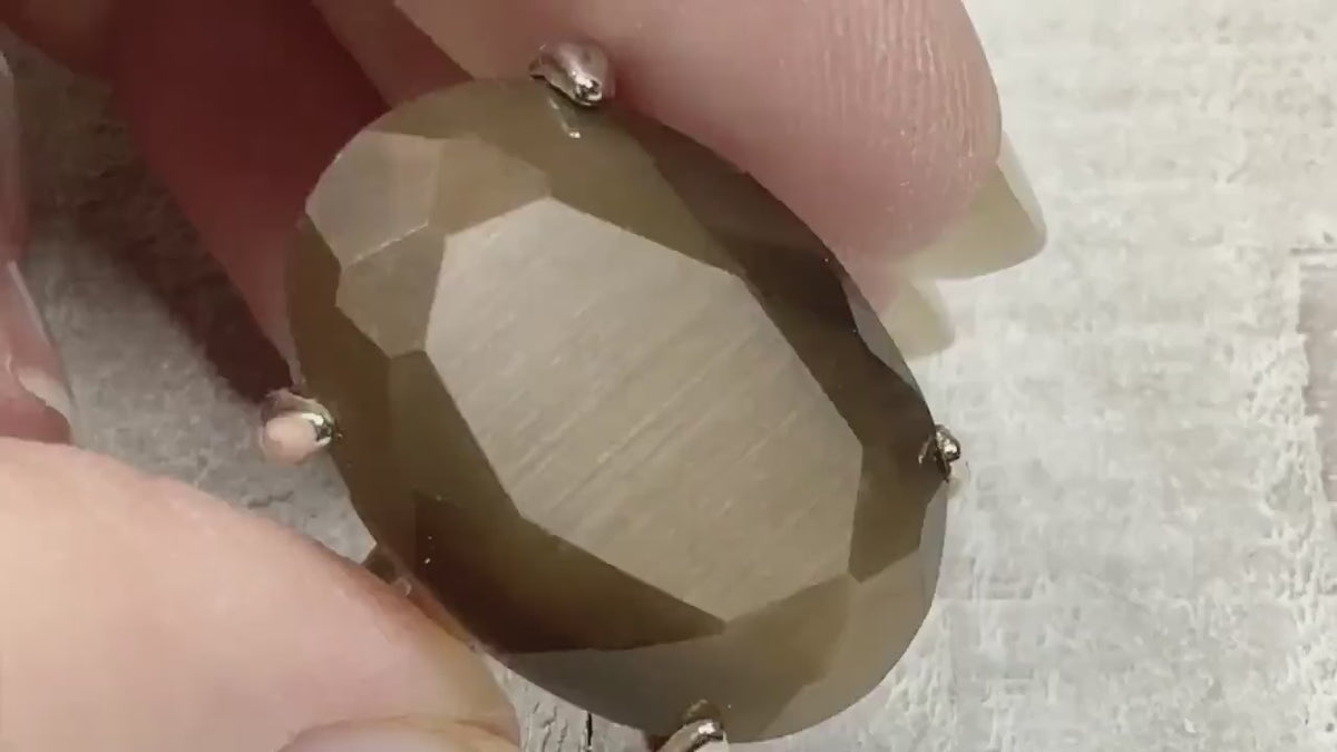Video showing the flash on the imitation cats eye retro vintage ring. The faux cat's eye stone is a large oval faceted and brown.