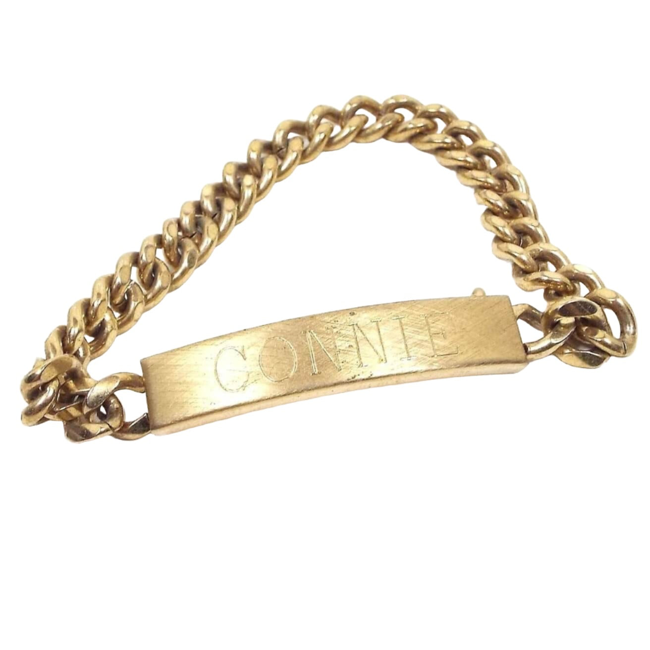 Front view of the Mid Century vintage Speidel ID bracelet. It is gold tone in color. The front curved bar has a brushed matte textured appearance and has the name Connie engraved on the front. There are some tiny spots and scuff scratches from age when viewed closely. 