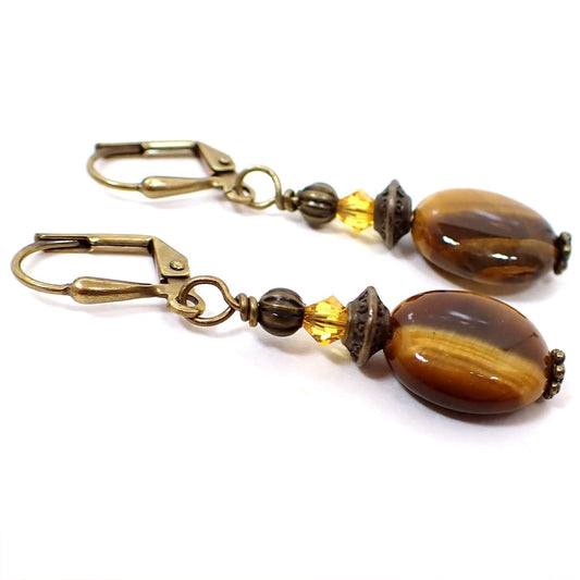 Side view of the handmade gemstone earrings. The metal is antiqued brass in color. There are faceted yellow glass crystal beads at the top. The bottom beads are oval tiger's eye and have shades of brown and yellow that have a shimmer effect as you move around in the light.