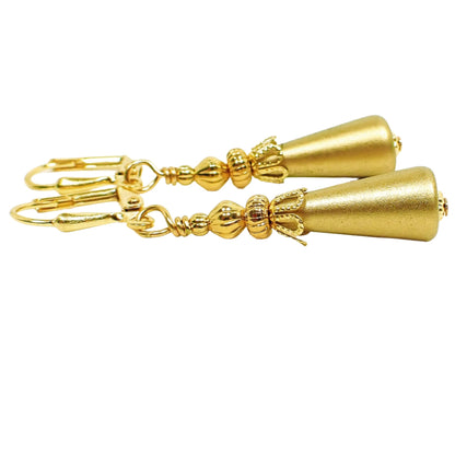 Side view of the handmade cone earrings. The metal is gold plated. The lucite plastic drops are cone shaped and antiqued gold in color.