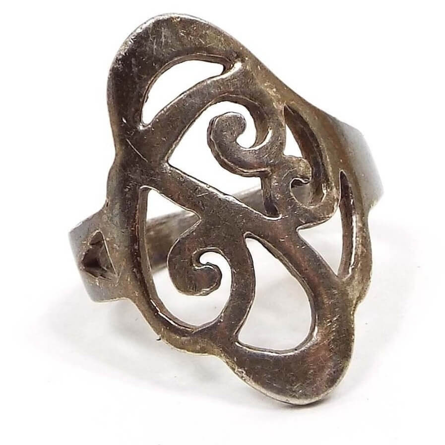 Front view of the retro vintage sterling silver filigree ring. The silver is darkened from age. There is a cut out curl design on the top. The filigree part is fairly wide with rounded corners. 