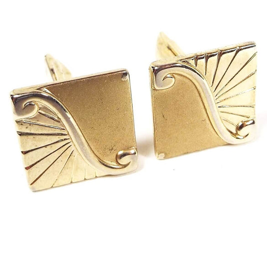 Front view of the Mid Century Vintage Pioneer cufflinks. They are gold tone in color and shaped like squares. The design is split diagonally with a shiny metal area curled at the ends. One side is shiny gold tone metal with diagonal cut lines and the other is matte gold tone in color.