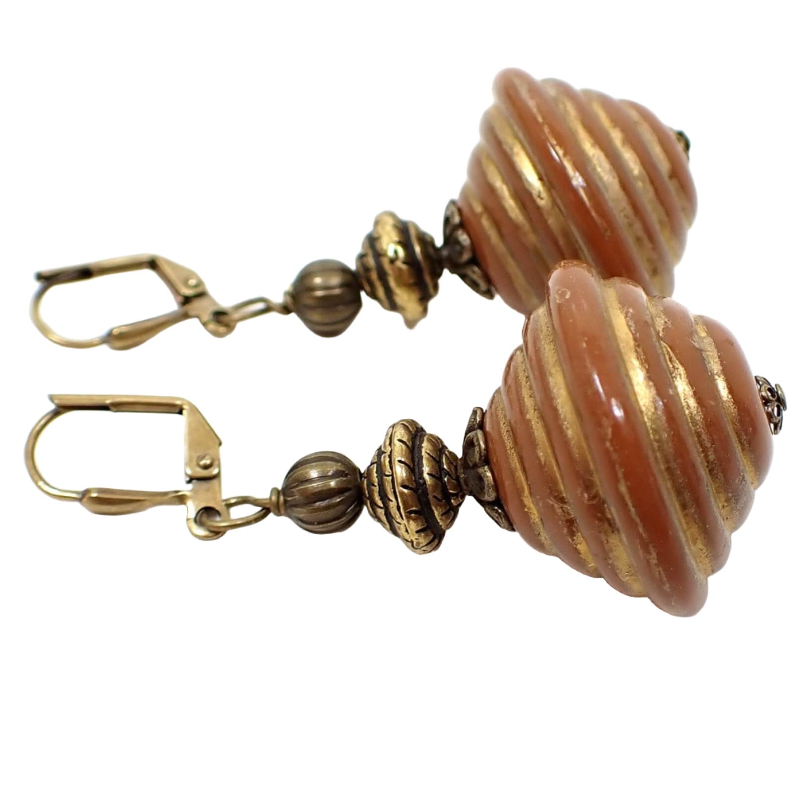 Side view of the handmade large chunky drop earrings. The bottom acrylic beads are large corrugated bicone shaped and are burnt orange in color with antiqued gold tone trim. 