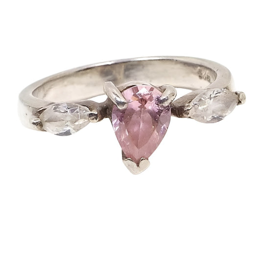 Front view of the retro vintage sterling silver cubic zirconia ring. The sides of the band have flat sides. The top has a prong set pear cut CZ stone in light pink. There is a prong set marquis cut clear CZ stones on each side. 925 is marked on the inside of the band.