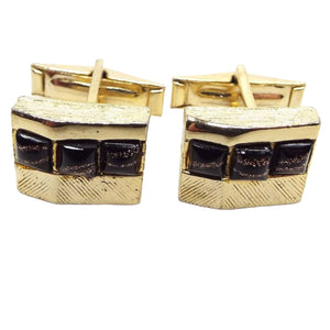 Front view of the retro vintage cufflinks with fancy glass cabs. The cufflinks are gold tone in color and are square with an angle on the front. There are three square glass cabs on each that are black with stripes of copper color glitter. No two cabs look the same. 