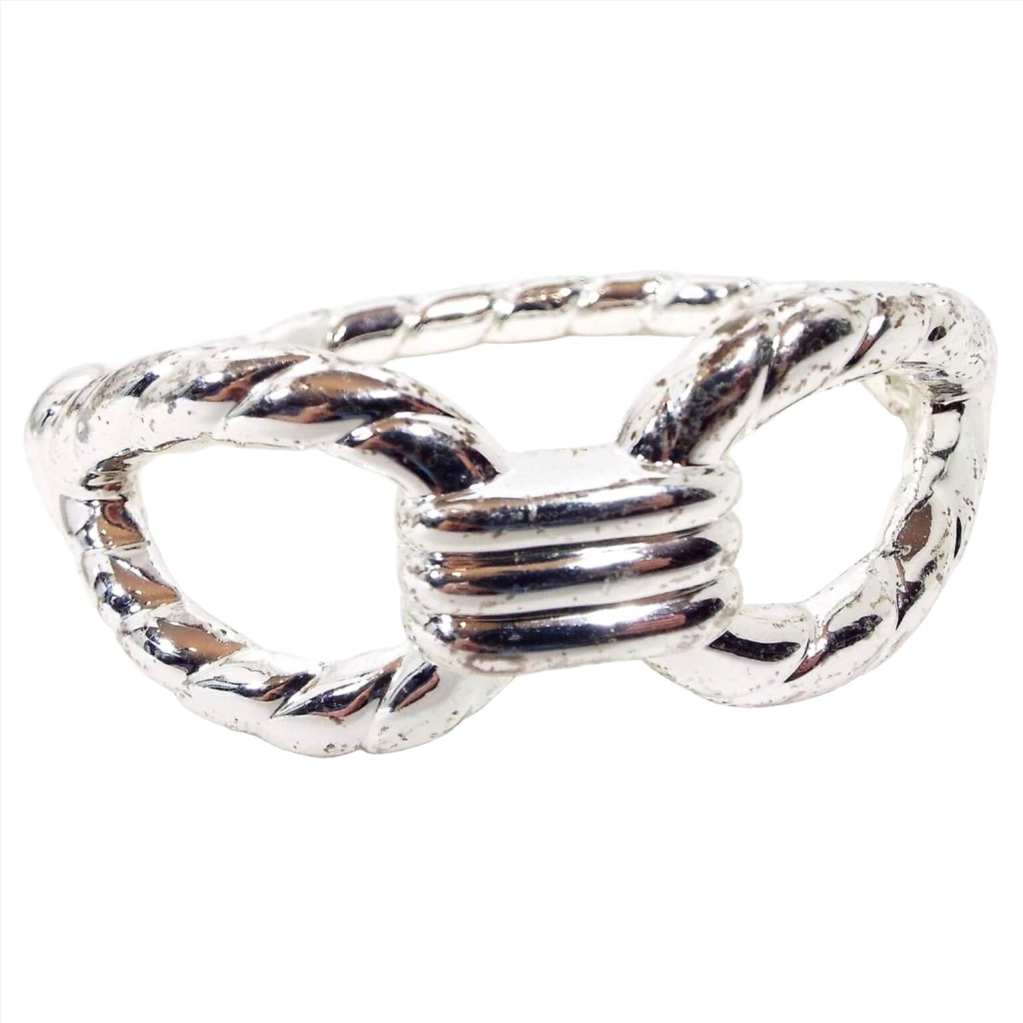 Front view of the retro vintage clamper bracelet, It is silver tone in color with a few tiny spots where it's darkening from age. It has a twisted rope like design that has a large open area on each side. The hinged part of the bracelet is on the side of the bracelet.