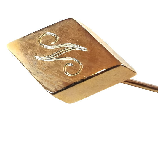 Enlarged view of the top of the Mid Century vintage initial stick pin. The metal is gold tone in color. There is a diamond shape at the top with the letter S engraved on it in fancy script.
