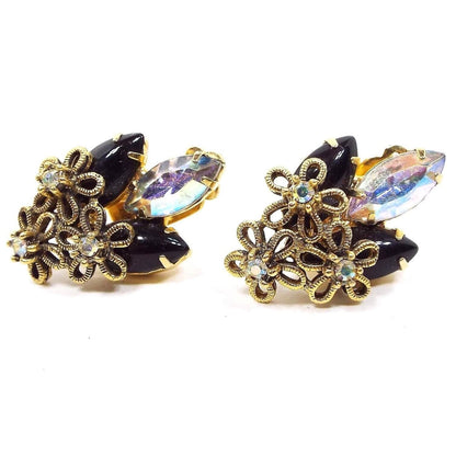 Front view of the Mid Century vintage rhinestone earrings. The metal is gold tone in color and has three flowers at the bottom of each earring. Each flower has an AB rhinestone in the middle. At the top of the earrings are two marquis smooth cab black rhinestones with an AB marquis rhinestone in the middle.