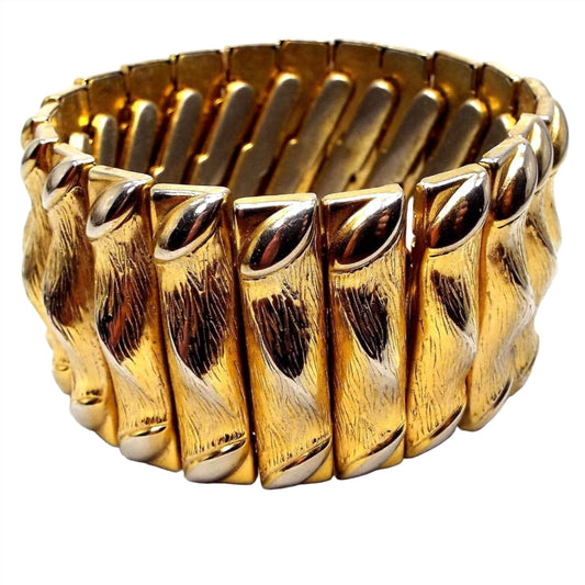Front view of the retro vintage expansion bracelet. It has wide textured gold tone metal rectangle links that and an oval shape on each side and a twist like design in the middle.