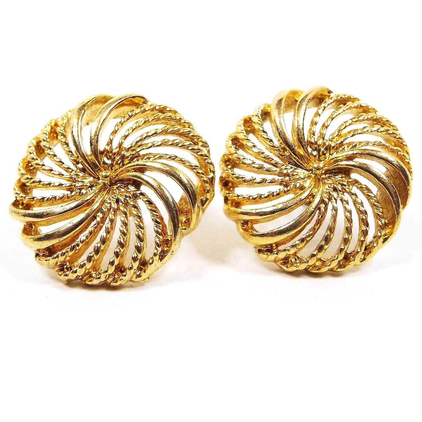 Front view of the retro vintage Napier post earrings. The are rounded filigree pinwheel shape with gold tone color metal.