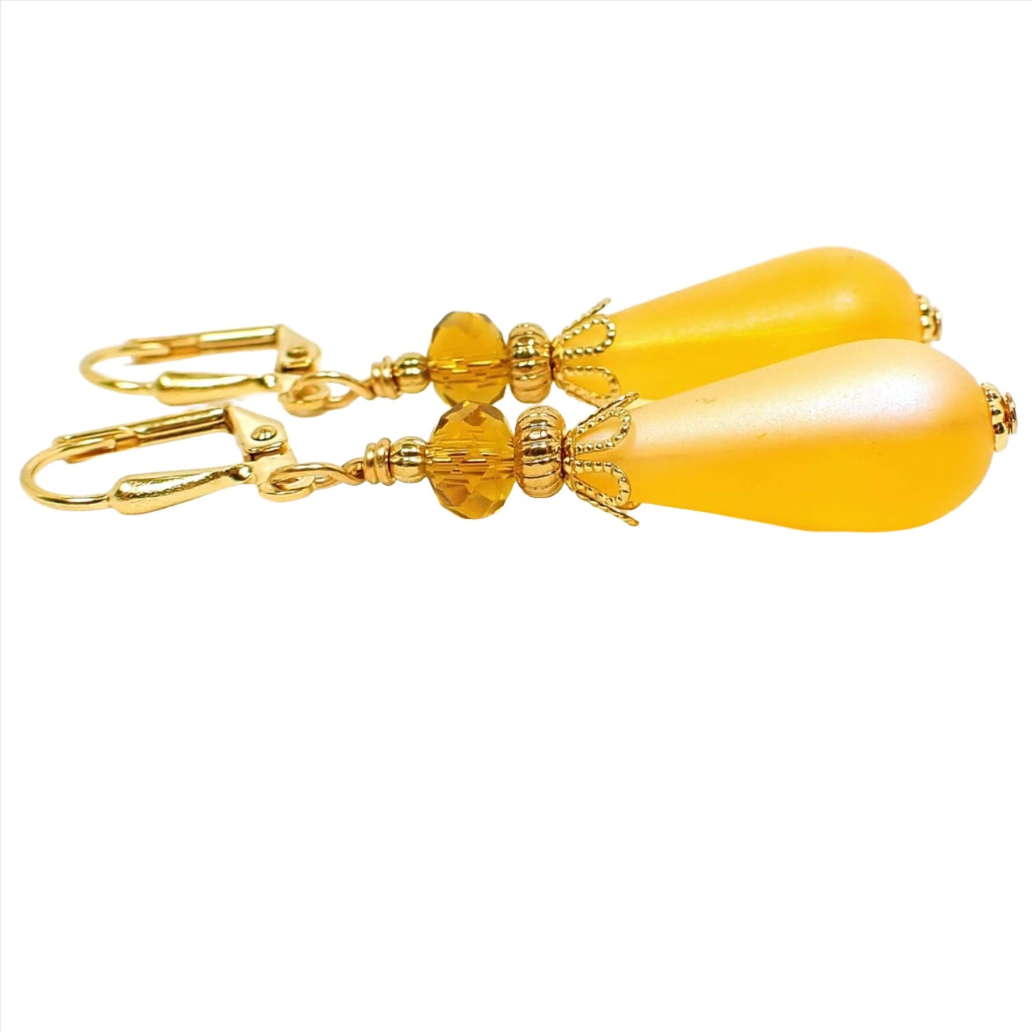 Side view of the handmade teardrop earrings. The metal is gold plated in color. The top beads are small faceted glass dark orange beads and the bottom beads are a frosted rich yellow lucite teardrop bead. 