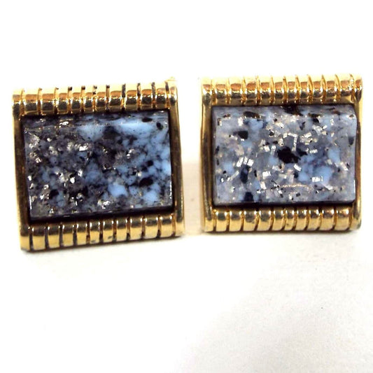 Front view of the retro vintage confetti lucite cufflinks. The metal is gold tone in color. The lucite cabs are mostly blue with black and gray marbled in as well as some silver glitter flakes.