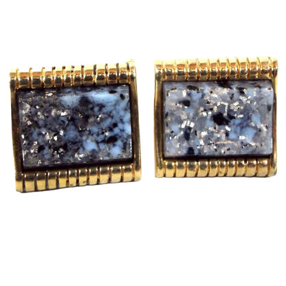 Front view of the retro vintage confetti lucite cufflinks. The metal is gold tone in color. The lucite cabs are mostly blue with black and gray marbled in as well as some silver glitter flakes.